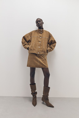 Tu-AW26-Model-08 - Tobacco Denim Funnel-Neck Trucker Jacket £32, Tobacco Denim Co-ord Mini Skirt £20, Heritage Tan Suede Bowler Bag £38, Suede Point-Toe Long Boot £60